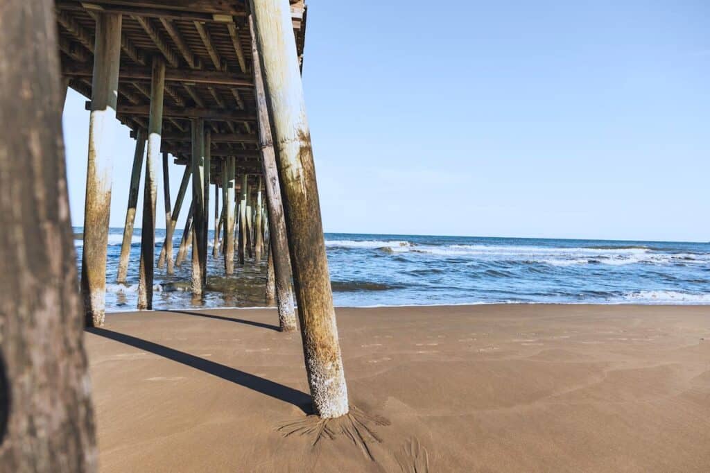 A beach with a pier and sand under it.